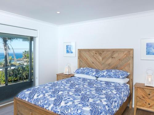 a bedroom with a blue and white bed and a window at Aqua Palm with Sweeping One Mile Views in Forster