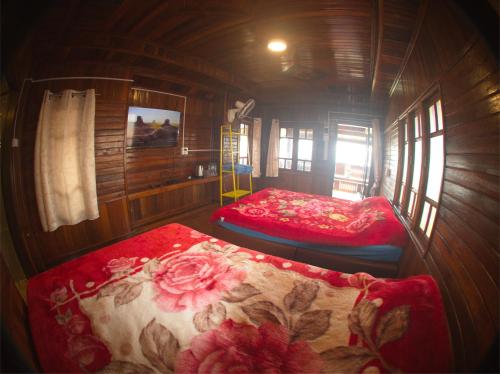 a bedroom with two beds in a wooden cabin at ไร่กะหล่ำหวาน ภูทับเบิก in Ban Phu Pun