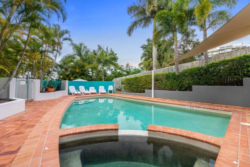 una piscina en un patio con palmeras en Kings Bay Apartments, en Caloundra