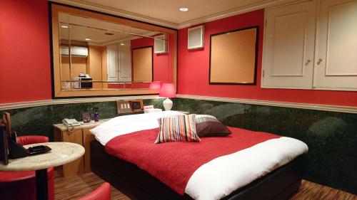 a bedroom with red walls and a bed with a table at Hotel Savoy - Adult Only in Tokyo