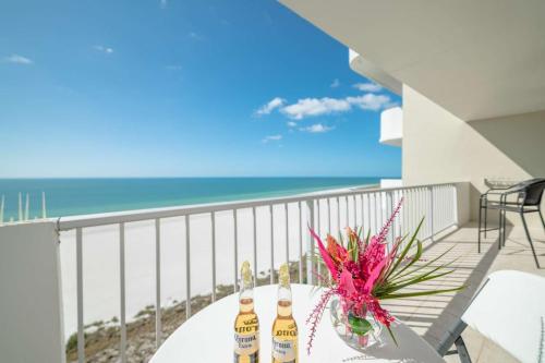 two bottles of beer on a table on a balcony with the beach at Admiralty House 1705S in Marco Island