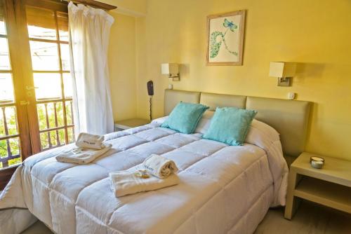 1 dormitorio con 1 cama blanca grande y toallas. en Hotel Edith en Villa Gesell
