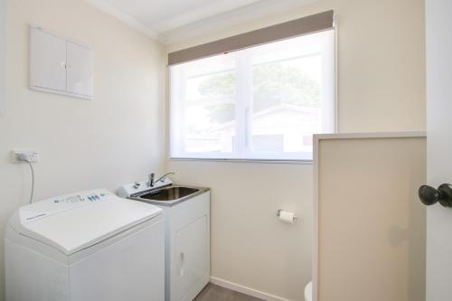 a small white kitchen with a sink and a window at Mama and Papa's - Havelock North Holiday Home in Havelock North