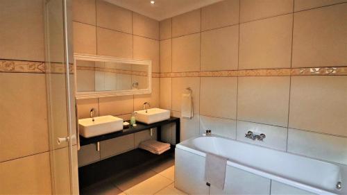 a bathroom with two sinks and a bath tub at Guest House Mamma Mia in Nelspruit