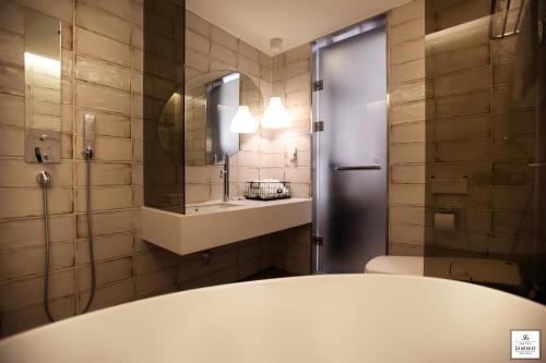 La salle de bains est pourvue de toilettes, d'un lavabo et d'un miroir. dans l'établissement Londoner Hotel Gwangan, à Busan
