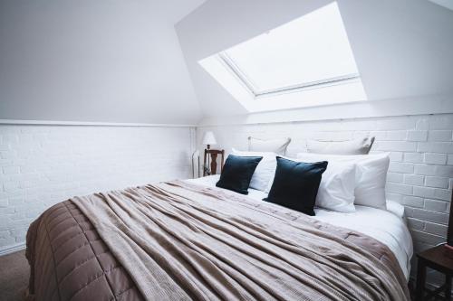 Dormitorio blanco con cama grande con almohadas negras en The Loft en Castlemaine
