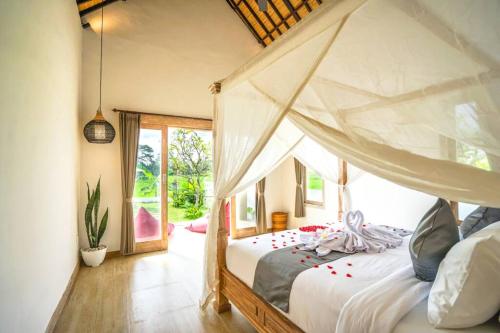 - une chambre avec un lit à baldaquin dans l'établissement 2 BR Villa with open view of rice paddies & sunset, à Gianyar