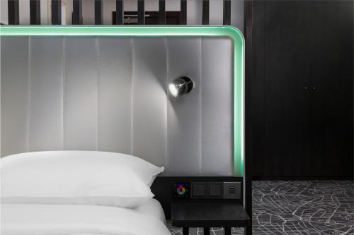 a bed with a headboard with a green light on it at Park Inn by Radisson Jeddah Madinah Road in Jeddah