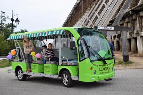 a green shuttle bus with people riding in it at Boutique Odyseja & Spa in Ciechocinek