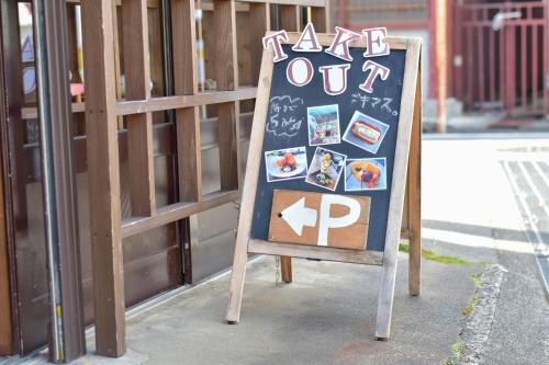a sign sitting on the sidewalk next to a fence at Ichie in Tanabe