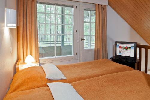 1 dormitorio con 1 cama grande de color naranja y ventana en Holiday Club Kalajoki Cottages, en Kalajoki