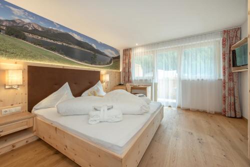 a bedroom with a large bed with towels on it at Hotel Theiner in Curon Venosta