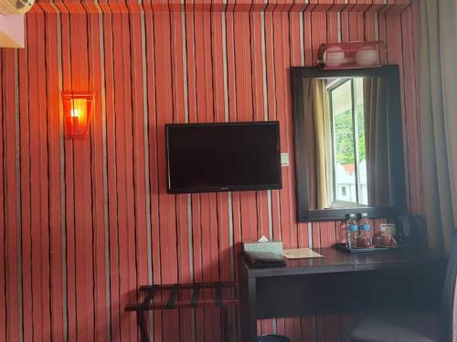 a room with a television on a wall with a mirror at 2 Inn 1 Boutique Hotel & Spa in Sandakan