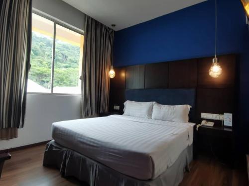 1 dormitorio con 1 cama grande y pared azul en 2 Inn 1 Boutique Hotel & Spa, en Sandakan