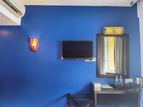 a room with a blue wall with a tv and a desk at 2 Inn 1 Boutique Hotel & Spa in Sandakan