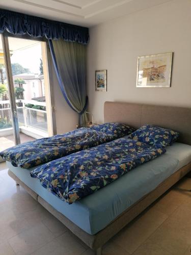 Condominio Golfo d'Oro في أسكونا: غرفة نوم بسرير وملاءات زرقاء ونافذة