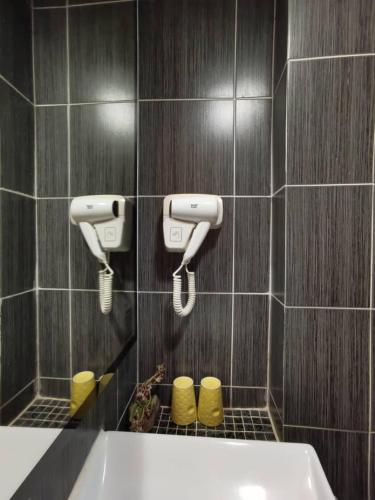 a bathroom with a tub and two hair dryers on the wall at 2 Inn 1 Boutique Hotel & Spa in Sandakan