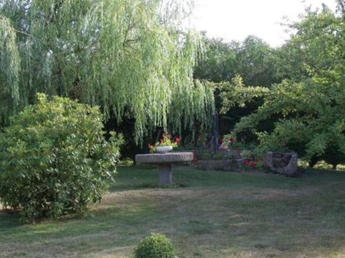 a bench in the middle of a yard with flowers on it at Le Mont Roti Chambres d’Hôtes in Faverolles