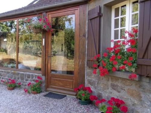 eine Holztür mit Blumen an der Seite eines Hauses in der Unterkunft Le Mont Roti Chambres d’Hôtes in Faverolles