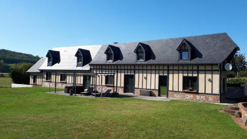 una casa con techo de gambrel y césped en La Longère Des Nuits De Varenne, en Muchedent