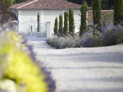 un jardin avec des fleurs violettes et une maison blanche dans l'établissement Château La Rose Perrière, à Lussac