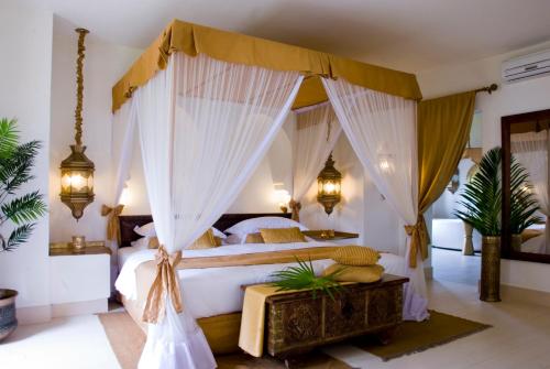 a bedroom with a canopy bed with curtains at Baraza Resort and Spa Zanzibar in Bwejuu