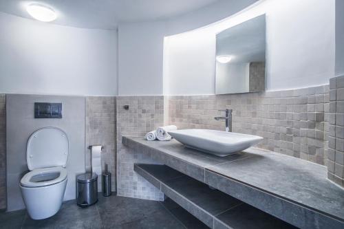 een badkamer met een wastafel, een toilet en een spiegel bij Island Kavos in Kavos