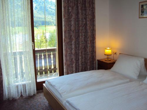a bedroom with a bed and a window with a balcony at Haus Alpenfriede in Weissensee