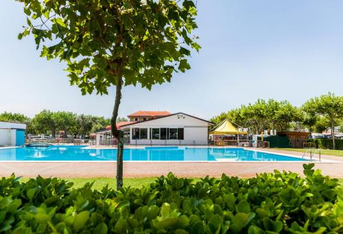 una piscina con un árbol en el primer plano en Miramare Camping Village, en Sottomarina