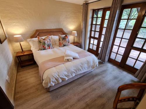 een slaapkamer met een groot bed in een kamer met ramen bij Migrate Portfolio in Dullstroom