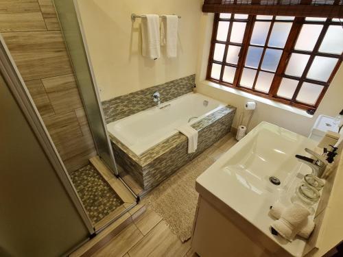 a bathroom with a tub and a sink at Migrate Portfolio in Dullstroom