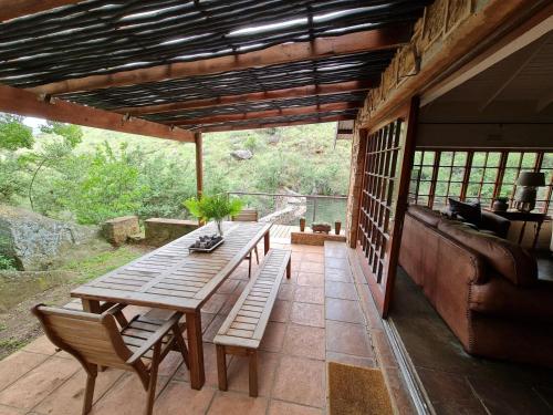 a patio with a wooden table and a couch at Migrate Portfolio in Dullstroom