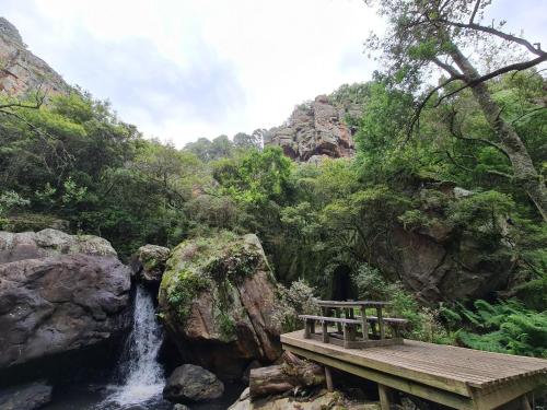 a bench sitting on a bridge next to a waterfall at Migrate Portfolio in Dullstroom