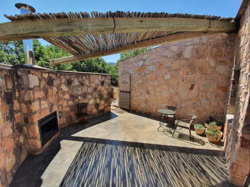 a patio with a brick wall and a table and chairs at Migrate Portfolio in Dullstroom