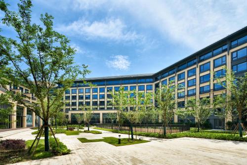 un edificio de oficinas con árboles delante de él en Q-Box Hotel Shanghai Sanjiagang -Offer Pudong International Airport and Disney shuttle en Shanghái