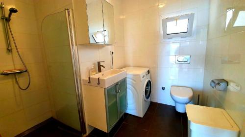 un piccolo bagno con lavatrice e lavandino di Bougainvilla Ground floor a Çeşme