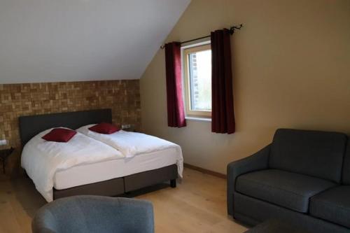 a bedroom with a bed and a couch and a window at Apparthotel Perreveld in Brakel