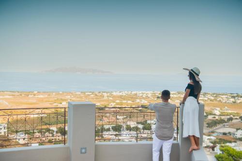 a man and woman standing on a balcony looking out at the city at Nano Suites in Éxo Goniá
