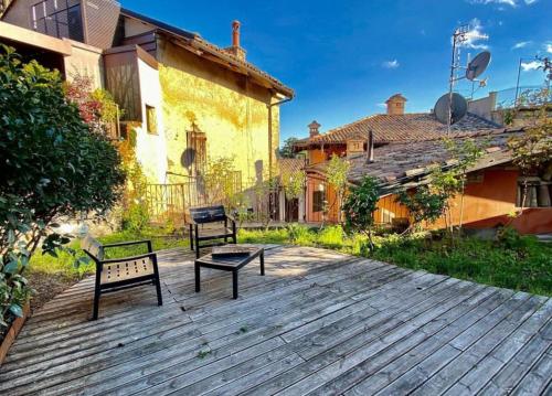 dos bancos sentados en una terraza de madera frente a una casa en Il Giardino sul Tetto B&B, en Guarene