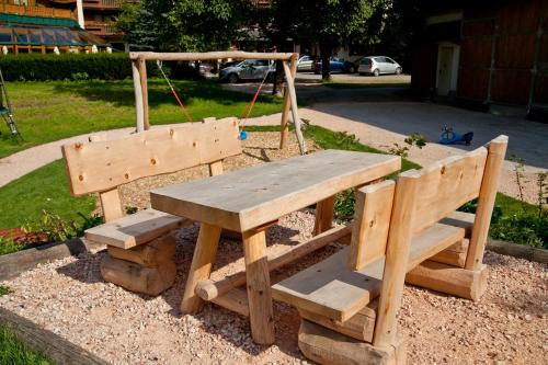 a wooden picnic table and bench with a swing at Ferienhotel Sonnenhof in Zell am Ziller