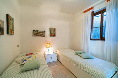 two beds in a bedroom with a lamp on a night stand at Appartamenti Vista Mare - Goelba in Capoliveri