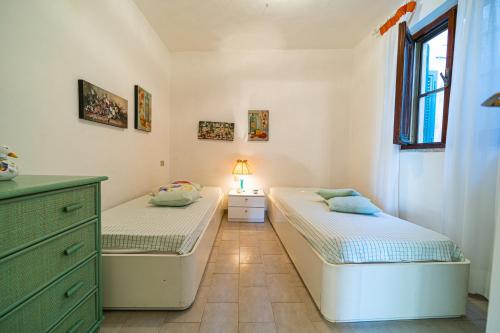 a bedroom with two beds and a dresser and a window at Appartamenti Vista Mare - Goelba in Capoliveri