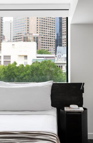 a bedroom with a bed with a view of a city at Lancemore Crossley St. Melbourne in Melbourne