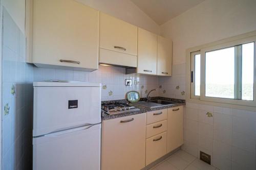 a kitchen with a white refrigerator and a window at Appartamenti Vista Mare - Goelba in Capoliveri