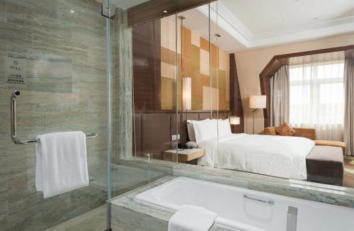 a bathroom with a bath tub and a bedroom at Hai Tian Expo Hotel in Qingdao