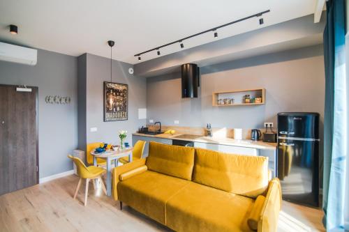 a living room with a yellow couch and a kitchen at Apartamenty River View od WroclawApartament-pl in Wrocław