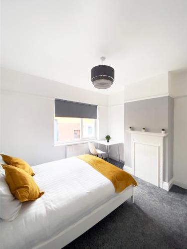 a white bedroom with a large bed with yellow pillows at The Baltic Townhouses by Serviced Living Liverpool in Liverpool