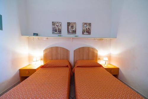 two beds in a small bedroom with two lamps at Appartamenti Vista Mare - Goelba in Capoliveri