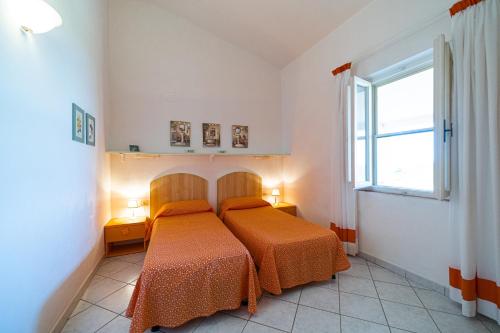 a bedroom with a bed with orange sheets and a window at Appartamenti Vista Mare - Goelba in Capoliveri
