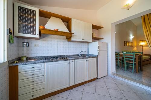 a kitchen with white cabinets and a white refrigerator at Appartamenti Vista Mare - Goelba in Capoliveri